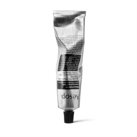 Un tube argente froisse d’Aesop Resurrection Aromatique Hand Balm, pose sur son bouchon noir, sur fond blanc.