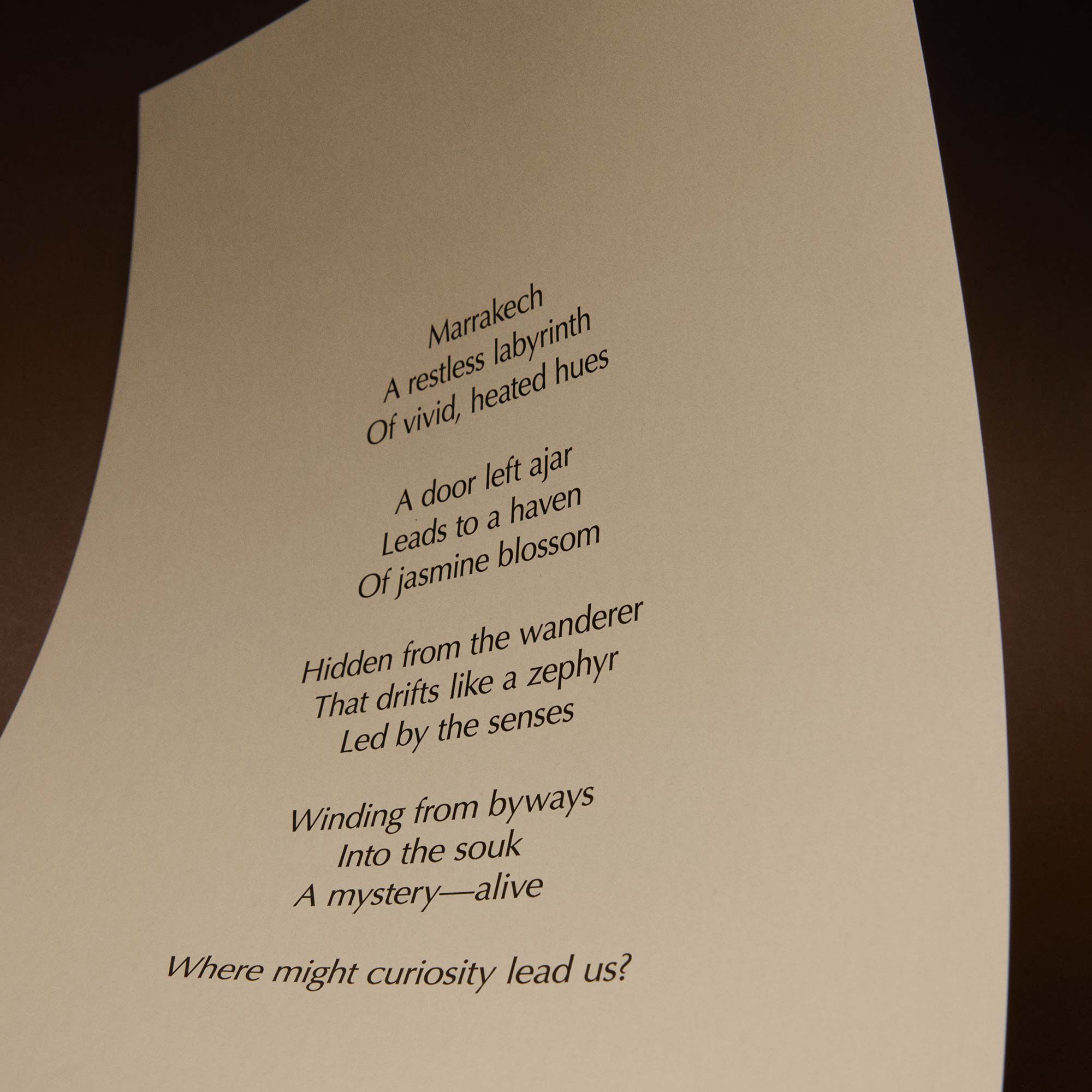 Curved cream page with printed verse against a dark brown background.
