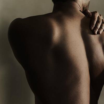 Person's bare back with one hand resting on their shoulder.