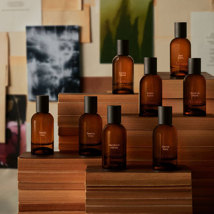Flacons de parfum en verre ambre Aesop exposes sur des livres empiles.