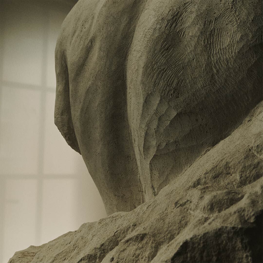 Close-up of a rough stone sculpture with soft window light in the background.