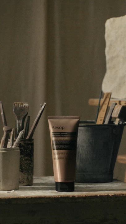 Aesop Antithesis Intense Body Cleanser tube on a work table with brushes and stone sculptures.